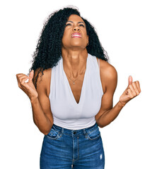 Middle age african american woman wearing casual style with sleeveless shirt crazy and mad shouting and yelling with aggressive expression and arms raised. frustration concept.