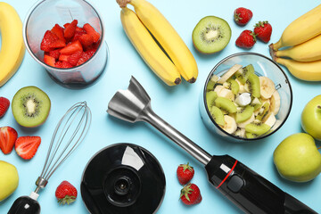 Hand blender kit, fresh fruits and strawberries on light blue background, flat lay