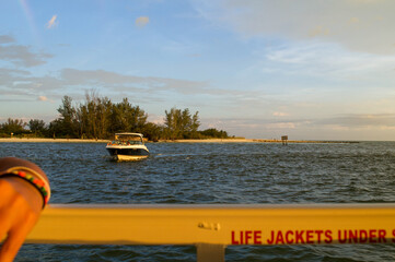 Fototapeta premium Boat seen crossing the Gulf of Mexico from the point of view of another viewer on a boat. Occurring as the sun is setting. 