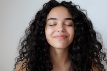 Naklejka premium Woman with curly hair enjoying peaceful moment with closed eyes relaxation concept