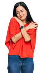 Beautiful young woman wearing casual clothes hugging oneself happy and positive, smiling confident....