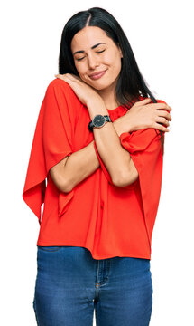 Beautiful young woman wearing casual clothes hugging oneself happy and positive, smiling confident. self love and self care