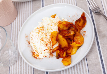 Appetizing pieces of baked apple with cottage cheese served on platter for breakfast