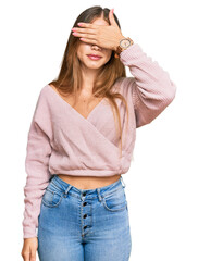 Beautiful blonde woman wearing casual winter pink sweater covering eyes with hand, looking serious and sad. sightless, hiding and rejection concept