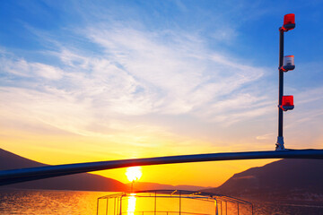Boat is sailing on a calm sea with a beautiful sunset in the background. Illuminated boat sailing in the twilight