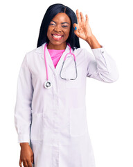 Young african american woman wearing doctor stethoscope smiling positive doing ok sign with hand and fingers. successful expression.