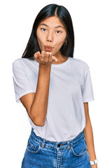 Beautiful young asian woman wearing casual white t shirt looking at the camera blowing a kiss with hand on air being lovely and sexy. love expression.