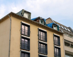 Obraz premium Facade of an apartment building prepared for renovation, featuring professional insulation, newly installed windows, and a rooftop set for repair.