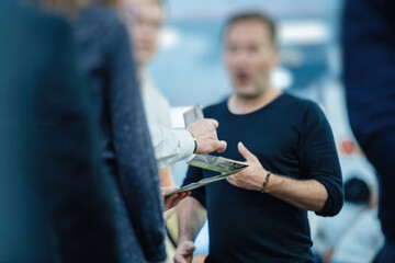 Silhouettes of people engaged in a serious conversation about a merger and acquisition deal at a fair