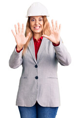 Beautiful young woman wearing architect hardhat afraid and terrified with fear expression stop gesture with hands, shouting in shock. panic concept.