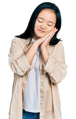 Young chinese woman wearing casual white t shirt and jacket sleeping tired dreaming and posing with hands together while smiling with closed eyes.