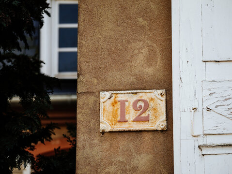 A house 12 twelve number sign is affixed to the side of a building, indicating the address of the property in a clear and prominently displayed manner