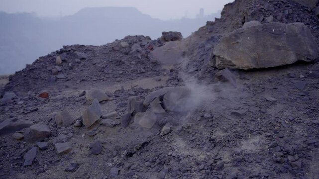 Jharia Coal mine with smoke and burning embers coming from the underground coal field fire