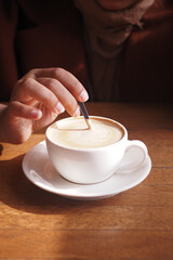person hand stirring coffee with spoon.