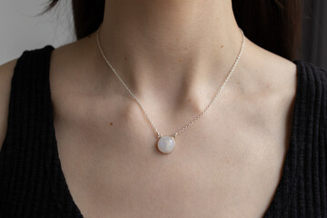 Silver necklace with moonstone on female neck. Model posing with jewelry. Elegant shiny pendant on...