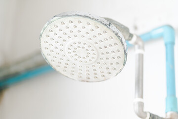 Close up old rain shower head clogged with many limestone and dirty stain.