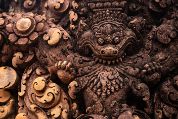 Detailed carved bas relief in red sandstone of mythological Kala at Banteay Srei -citadel of women and beauty- Hindu Temple dedicated to god Shiva and Parvati, Siem Reap, Cambodia.