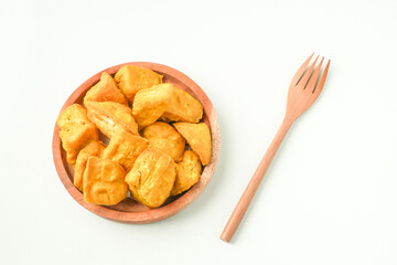 Flat Lay Photo of Fried yellow tofu served on wooden plate next to wooden fork. Tahu Takwa is a specialty food from Kediri, East Java, Indonesia. Concept for Plant based protein.