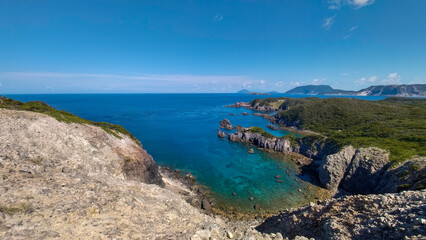 Obraz premium 島の北西端にある神引展望台。 高さ100mの断崖絶壁の上にある。 海側は180度広がる太平洋の海と島々。 陸側は荒涼とした荒れ地が広がる。 東京都にあるとは思えないダイナミックな風景。青い海と緑の森が美しい神引展望台から見る、式根島と新島の海。 中の浦海水浴場、神引浦。東京都伊豆諸島式根島-2020年10月3日 