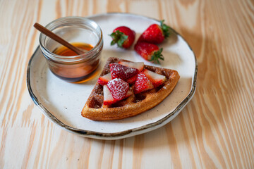freshly made breakfast on a beautiful morning with honey, strawberries, and waffles