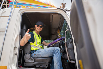 Asian happy professional truck driver driving his truck and looking at camera.