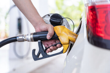 Close up hand of A male driver hand refilling and pumping gasoline oil the car with fuel at he refuel station. Car refueling on petrol station.