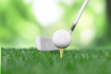 Golf clubs and balls on green lawn at course