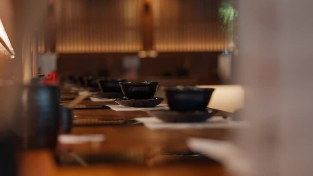 Elegant Japanese restaurant setup, featuring traditional decor, neatly arranged table settings, and a serene ambiance. Highlighting blend of modern and classic elements. High quality 4k footage