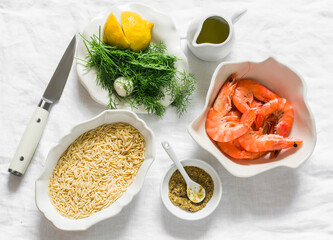 Ingredients for making orzo pasta with shrimp in dill-mustard-lemon marinade on a light surface