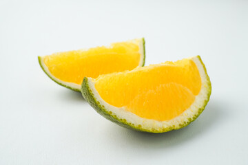 Two slices of fresh green colored orange (citrus sinensis) isolated on white background.