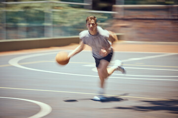 Fototapeta premium Basketball player, sports and training with a active, fit and fast man playing a game at an outdoor court. Professional athlete doing exercise for health and wellness during practice for a match