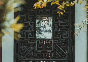 A close-up view of an intricately carved wooden window frame in a building. The frame is black with...