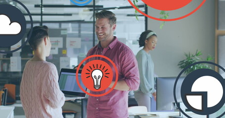 Image of icon in circles over diverse coworkers standing and discussing in office