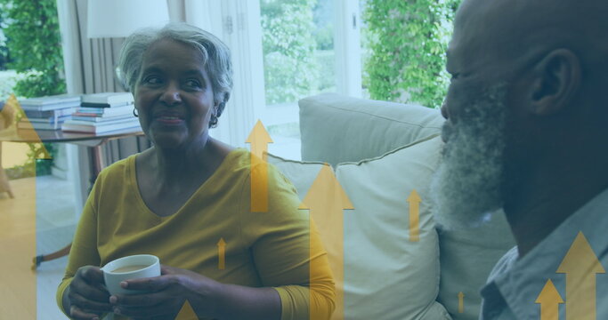Image of up arrow over diverse couple sitting on sofa and discussing while drinking coffee