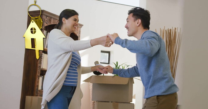 Image of gold house key and key fob over happy diverse couple dancing at new home - Powered by Adobe