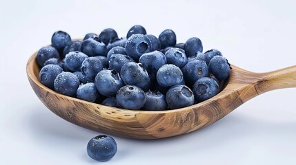Blueberries arranged on a wooden spoon and a plate create a natural and appealing display of fresh fruit.