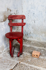 Cornered.  Old red wooden chair and a brick in a corner against a wall in So Heng Tai Mansion,...