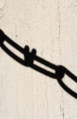 Shadow of a chain cast on a textured wall