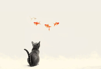 Obraz premium A cat sits on the floor looking up at a goldfish swimming in the air.