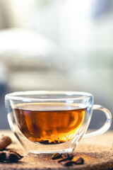 Close-up, glass cup of aromatic black tea on a blurred background.