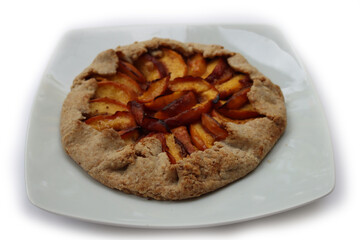 Homemade galette with peaches isolated on white background. Baked french open pie with summer fruits