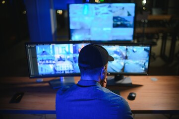 Security operator controls CCTV cameras in office at night. Modern security system and social...