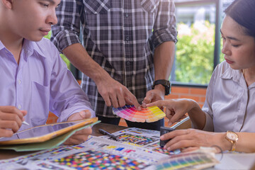 Worker checking print quality of media graphics proof print and color tone in printing industry. Selected focus