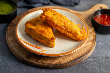 Selective Focus of Bread pakora is a popular Indian street food made with bread, stuffed with spicy potato filling, coated in chickpea flour, and deep-fried.