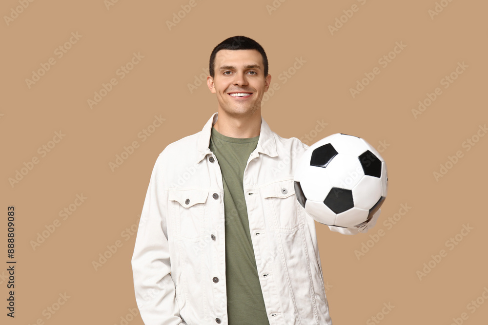 Wall mural handsome young man with soccer ball on brown background