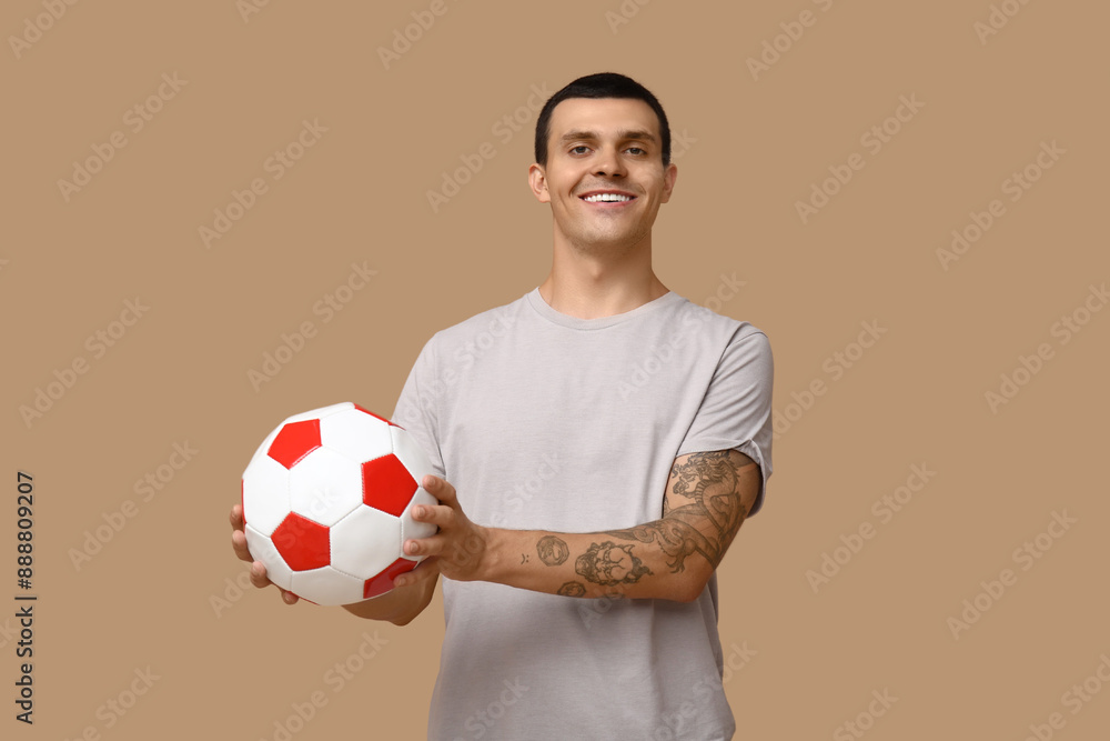 Wall mural handsome young man with soccer ball on brown background