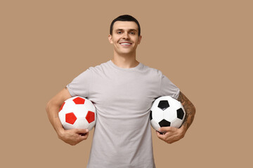Handsome young man with soccer balls on brown background
