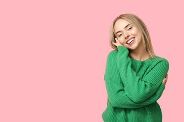 Young woman hugging herself on pink background