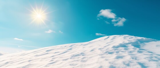  The sun shining brightly over a snow-covered hill on a clear day, with a brilliant blue sky as its backdrop
