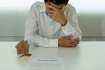 Business man is stressed due to imminent seizure of assets, debts, financial problems, loans, guarantees document with the text eviction notice, debt, property, loan, agent, bankruptcy.
